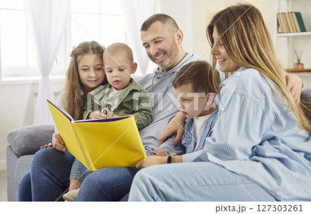 Children and parents reading book together at home for bonding, entertainment and quality time. 127303261