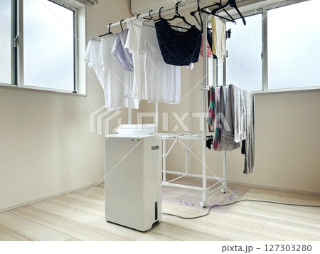 部屋に設置された物干しスタンドと稼働中の除湿機　梅雨時期の部屋干し 127303280