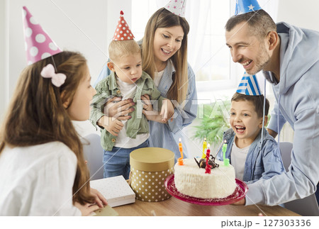Happy joyful family sitting at home together congratulating their little child girl with birthday Happy joyful family sitting at home together congratulating their little child girl with birthday 127303336