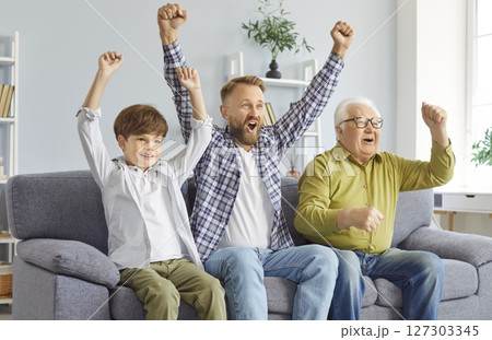 Three generations of men cheer energetically watching exciting sports competitions on TV. 127303345