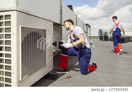 Worker Maintaining Air Conditioning System on Roof Worker Maintaining Air Conditioning System on Roof 127303391