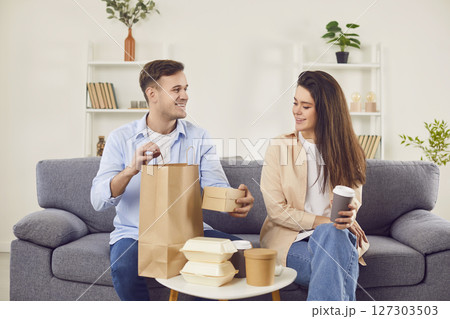 Happy young couple unpacking food from take out meal delivery cafe or restaurant 127303503