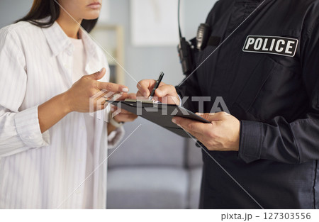 Police officer taking notes while interviewing woman who is witness or victim of house burglary Police officer taking notes while interviewing woman who is witness or victim of house burglary 127303556