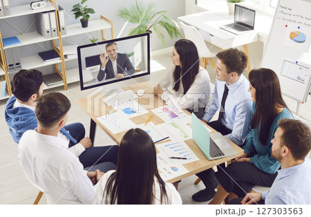 Business people having online videoconference in meeting room with man colleague sitting in office 127303563