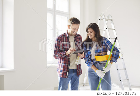 Happy young married couple tablet watching enjoying home renovation fun, repair after moving Happy young married couple tablet watching enjoying home renovation fun, repair after moving 127303575