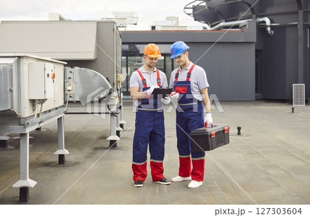 Positive Workmen Repairing And Servicing Hvac System On Roof 127303604