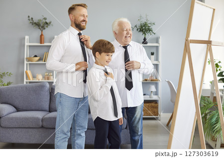 Three generations of men are gathered in front of mirror, each dressed in white shirt and black tie Three generations of men are gathered in front of mirror, each dressed in white shirt and black tie 127303619