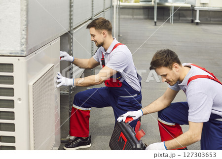 Air conditioning technicians are repairing and maintaining air conditioners on the roof. Air conditioning technicians are repairing and maintaining air conditioners on the roof. 127303653