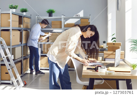 Two young employees are doing inventory management in small online store warehouse Two young employees are doing inventory management in small online store warehouse 127303761