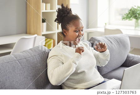 African-American Woman Celebrating Success Using A Laptop At Home 127303763
