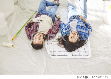 Top view of happy young couple lying on floor with paint rollers. Repair concept. Top view of happy young couple lying on floor with paint rollers. Repair concept. 127303839