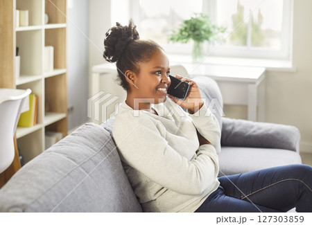 Young african american woman talking on phone at home, happy girl holding cellphone making call Young african american woman talking on phone at home, happy girl holding cellphone making call 127303859