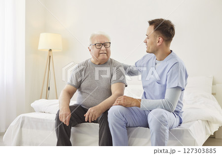 Friendly young male nurse consulting senior man after examining him in medical clinic. 127303885