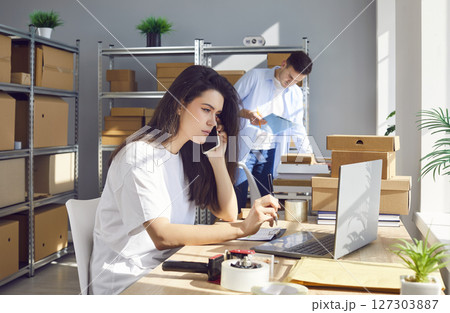 Serious Woman Working In Warehouse And Talking To Consumers On Phone Serious Woman Working In Warehouse And Talking To Consumers On Phone 127303887