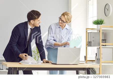 Two diverse office businesspeople chatting standing near laptop, sharing new ideas or startup  127303981