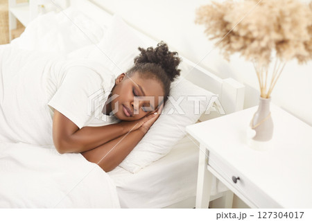 Young woman sleeping sweetly in cozy bedroom at modern home interior in the morning 127304017