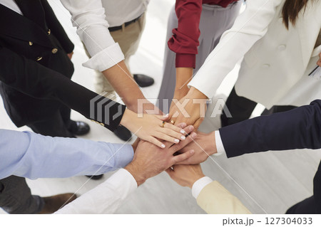 Top view of business people putting their arms together standing in office. 127304033