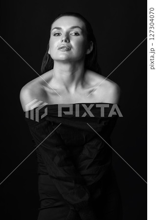 Seductive looking woman with dark clothes and wet hair studio portrait 127304070