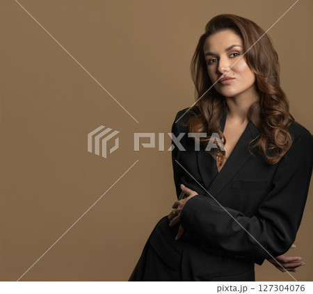 Woman with long wavy hair and black suit studio portrait on beige background Woman with long wavy hair and black suit studio portrait on beige background 127304076