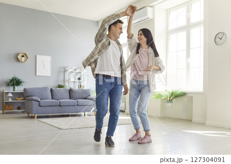 Happy laughing spouses dancing at home, having fun in new living room, playful and affectionate  Happy laughing spouses dancing at home, having fun in new living room, playful and affectionate  127304091