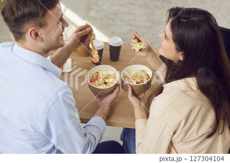 Happy young man and woman are talking happily while enjoying delicious takeaway. Happy young man and woman are talking happily while enjoying delicious takeaway. 127304104