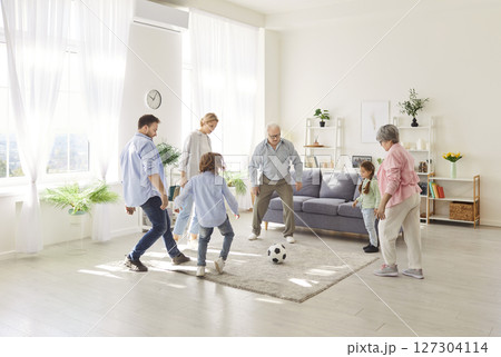 Active sporty happy funny family, three generation people, excited playing football at home 127304114