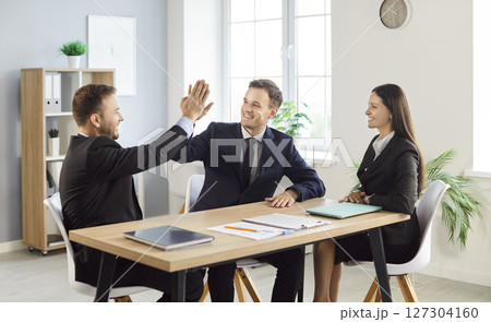Business people sitting in office making deal and giving high five finishing meeting Business people sitting in office making deal and giving high five finishing meeting 127304160