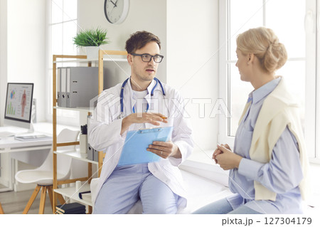 Young woman patient visiting male physician at doctor office during medical examination. Young woman patient visiting male physician at doctor office during medical examination. 127304179