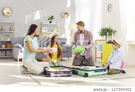 Happy family packing suitcases preparing for summer vacation trip sitting on floor at home. Happy family packing suitcases preparing for summer vacation trip sitting on floor at home. 127304302