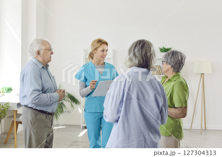 Elderly people listening young woman nurse or psychologist talking with seniors in nursing home. 127304313