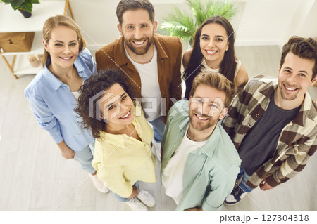 Top view portrait of a group of friends standing together at home and looking cheerful at camera. Top view portrait of a group of friends standing together at home and looking cheerful at camera. 127304318