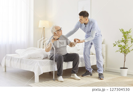 Nursing senior aged man at home, supporting young doctor, nurse taking care of old patient check  127304530