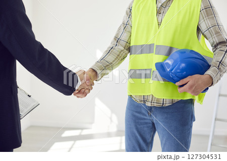 Foreman making deal with architect shaking hands standing in empty room at construction site Foreman making deal with architect shaking hands standing in empty room at construction site 127304531