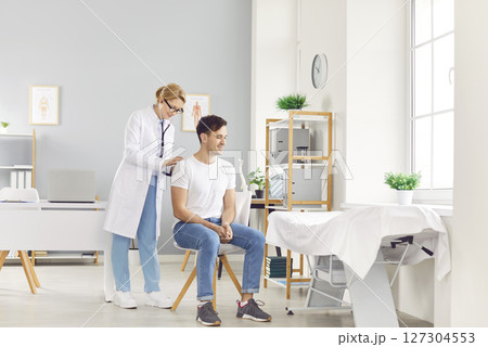 Doctor with stethoscope listening back to heart, lungs, male health care, female doctor clinic Doctor with stethoscope listening back to heart, lungs, male health care, female doctor clinic 127304553