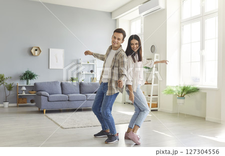 Portrait of happy smiling young couple having fun and dancing at home. Portrait of happy smiling young couple having fun and dancing at home. 127304556