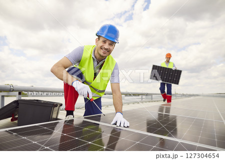 Portrait Of Smiling Worker Installing Or Servicing Solar Panels On Roof 127304654