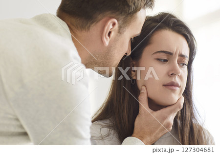 Upset young woman listening her annoyed husband touching her face. Domestic violence concept. 127304681