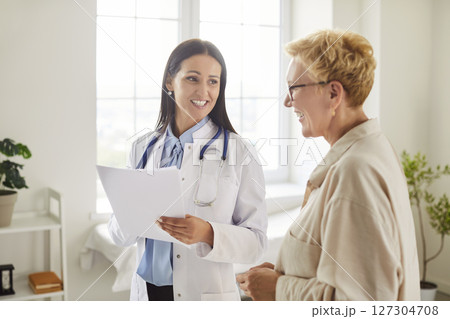 Doctor talking with mature woman patient standing in office during medical examination in clinic 127304708