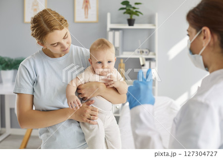 Mother with little child baby visiting doctor in medical clinic for examination before vaccination Mother with little child baby visiting doctor in medical clinic for examination before vaccination 127304727