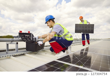 Workers Or Electricians Installing Or Maintaining Solar Panels On Roof Workers Or Electricians Installing Or Maintaining Solar Panels On Roof 127304754