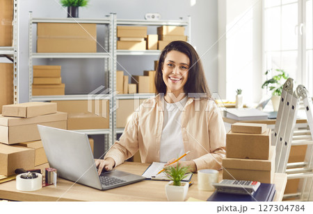 Woman working in warehouse checking stock and inventory sitting at the desk on workplace 127304784