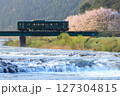 雪解け水の水量豊かな春の朝に満開の桜を背景に鉄橋を渡るローカル鉄道 127304815