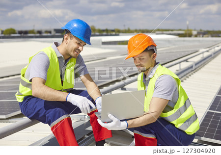 Electricians Configuring Solar Panels On Roof With Laptop 127304920