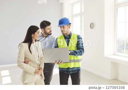 Foreman worker and family client supervises and directs worker meeting, looking at project plan 127305108