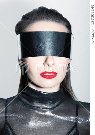 Abstract woman studio portrait with make-up and metallic eyeglasses or helmet covering her eyes 127305149