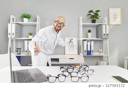 Optician with large round glasses invites you to check your vision using special table with letters. Optician with large round glasses invites you to check your vision using special table with letters. 127305172