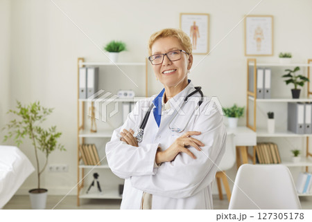 Portrait Of Smiling Elderly Doctor Or Nurse In A Hospital Office Portrait Of Smiling Elderly Doctor Or Nurse In A Hospital Office 127305178