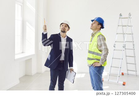 Engineer standing with foreman in room, pointing at something, consulting about renovation, design. 127305400
