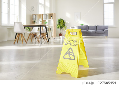 Yellow caution wet floor sign close up, office cleaning service, after cleaning floor at home Yellow caution wet floor sign close up, office cleaning service, after cleaning floor at home 127305454