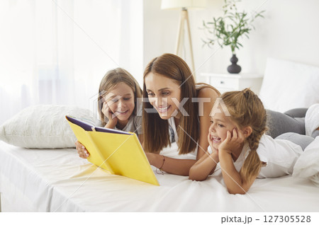 Mother And Kids Enjoying Morning Leisure In Bed Reading A Book At Home 127305528